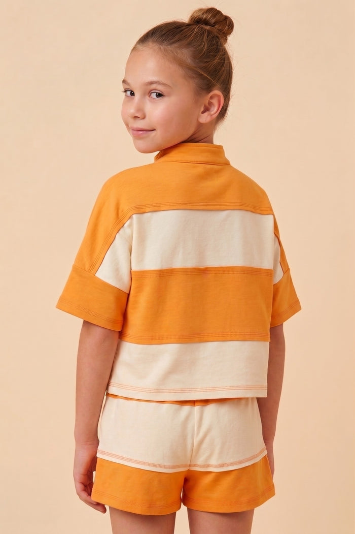 Young girl wearing an orange and beige outfit against a beige background
