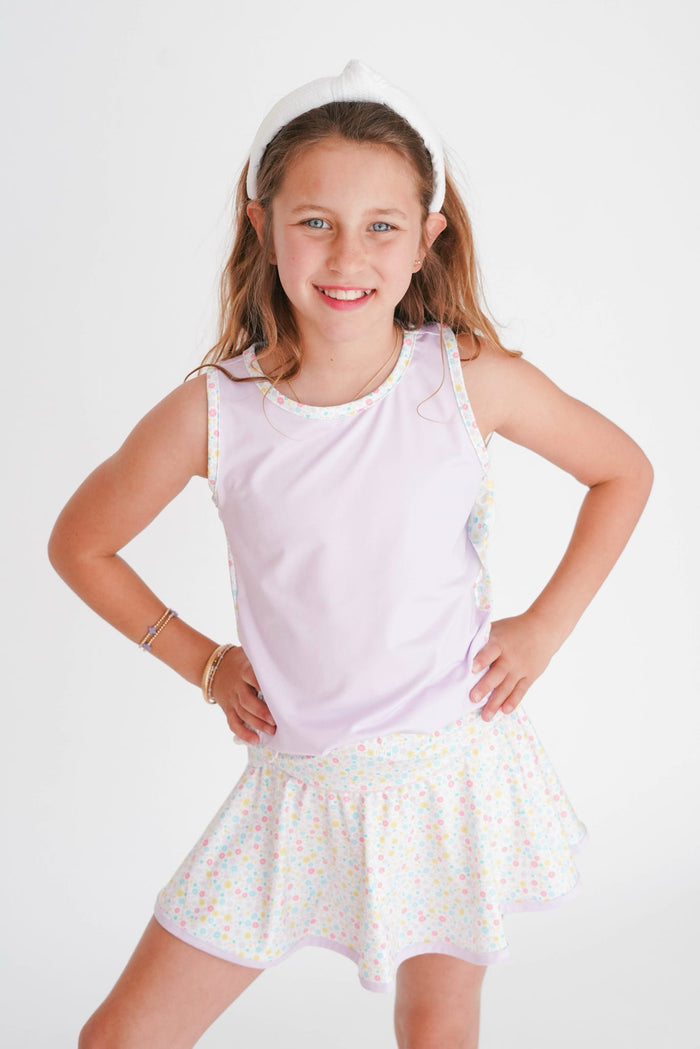 Young girl wearing a white sleeveless top and patterned skirt on a white background