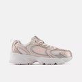 A New Balance low-top sneaker in a metallic rose gold and white colorway, shown from a side profile view against a light gray background.