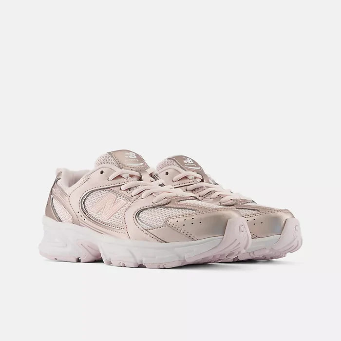 A pair of New Balance 9060 sneakers in a light metallic pink and beige colorway, shown from a three-quarters angle against a plain light gray background.