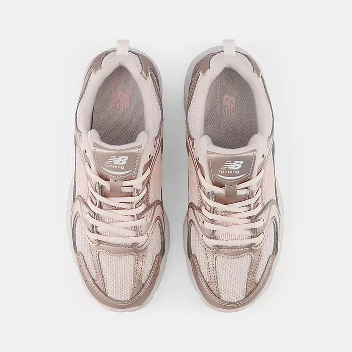 A pair of New Balance sneakers in a dusty rose and metallic rose gold colorway, shown from a top-down view on a light gray background.