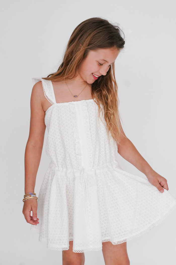 Young girl wearing a white dress against a plain background