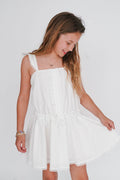 Young girl wearing a white dress against a plain background