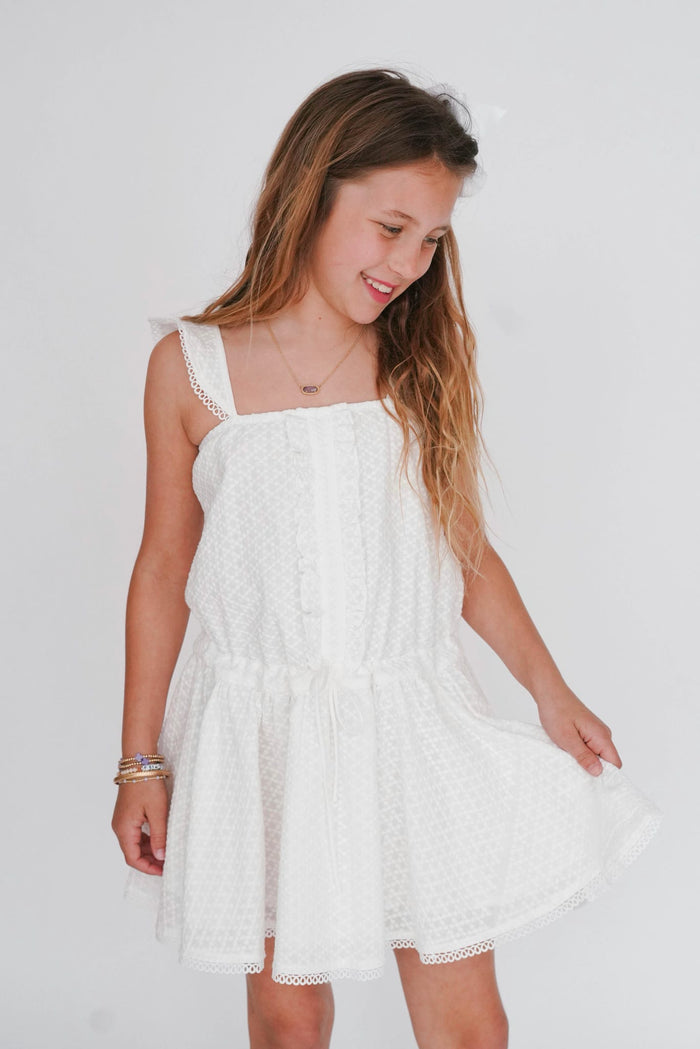 Young girl wearing a white dress against a plain background