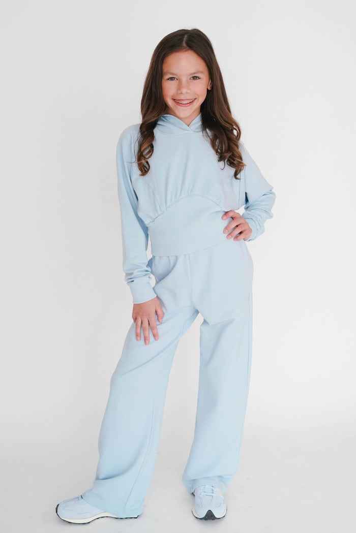 Young girl wearing a light blue onesie against a white background