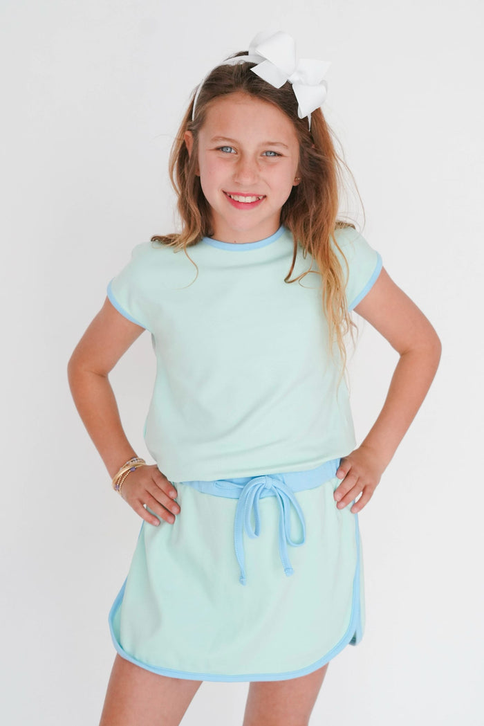 Young girl wearing a light blue outfit with a white background