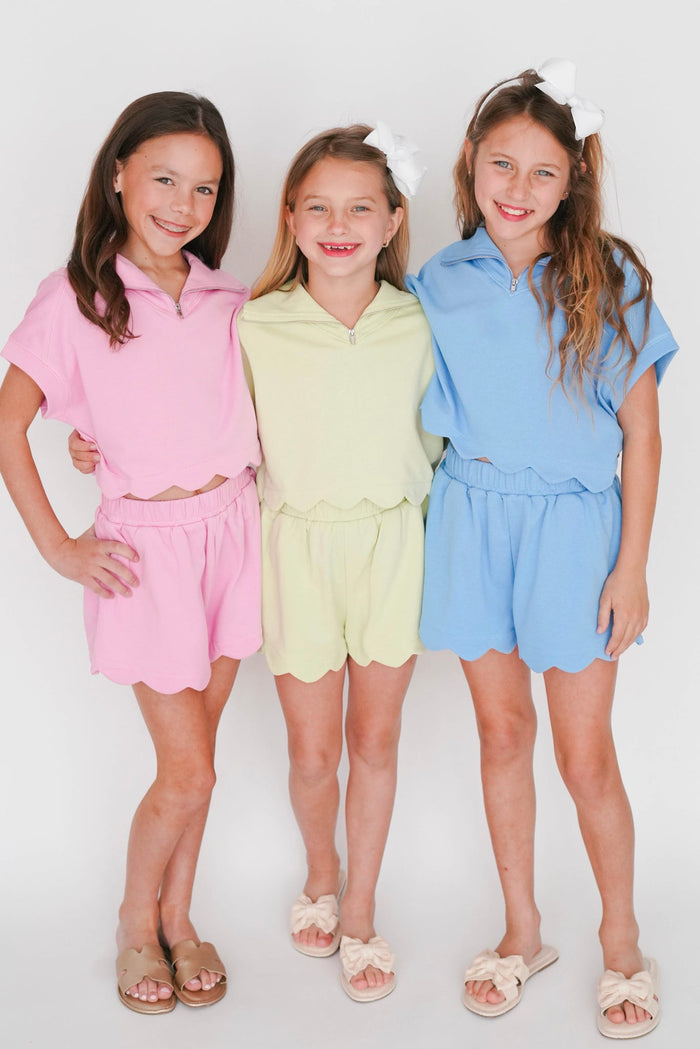 Three young girls wearing colorful outfits on a white background