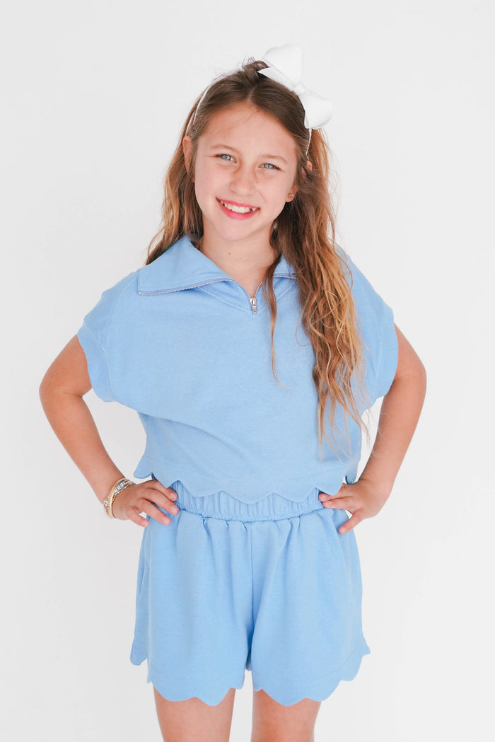 Young girl wearing a light blue outfit with a white background