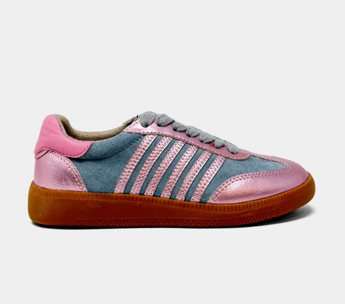 A low-top sneaker featuring a dusty blue suede upper with metallic pink leather side stripes, a pink heel tab, and a brown gum sole, shown against a light gray background.