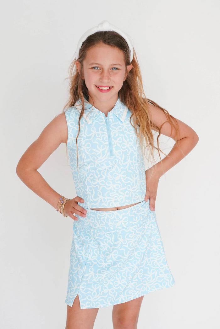 Young girl wearing a light blue floral dress with a white headband against a plain background