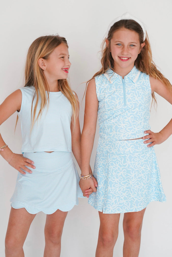 Two young girls wearing matching light blue outfits against a white background
