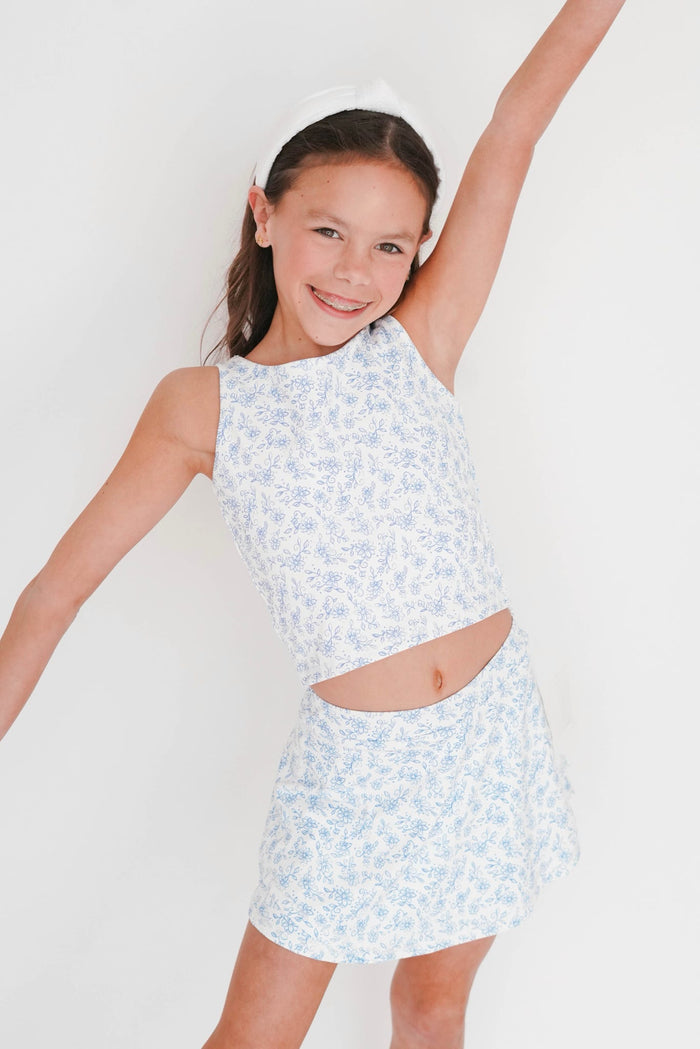 Young girl wearing a light blue floral dress against a white background