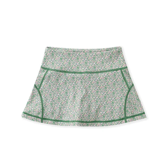 A high-waisted athletic skirt with a dense green, pink, and white floral pattern, featuring solid green contrast piping along the seams, displayed on a clean white background.