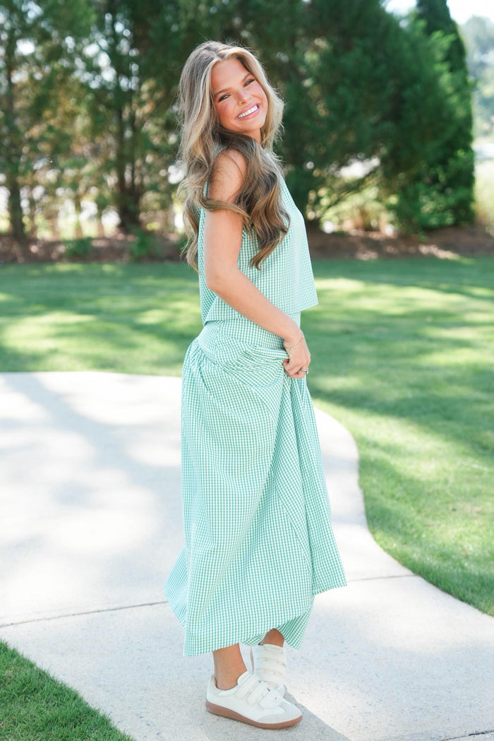 Woman in a light green dress standing outdoors on a sunny day.
