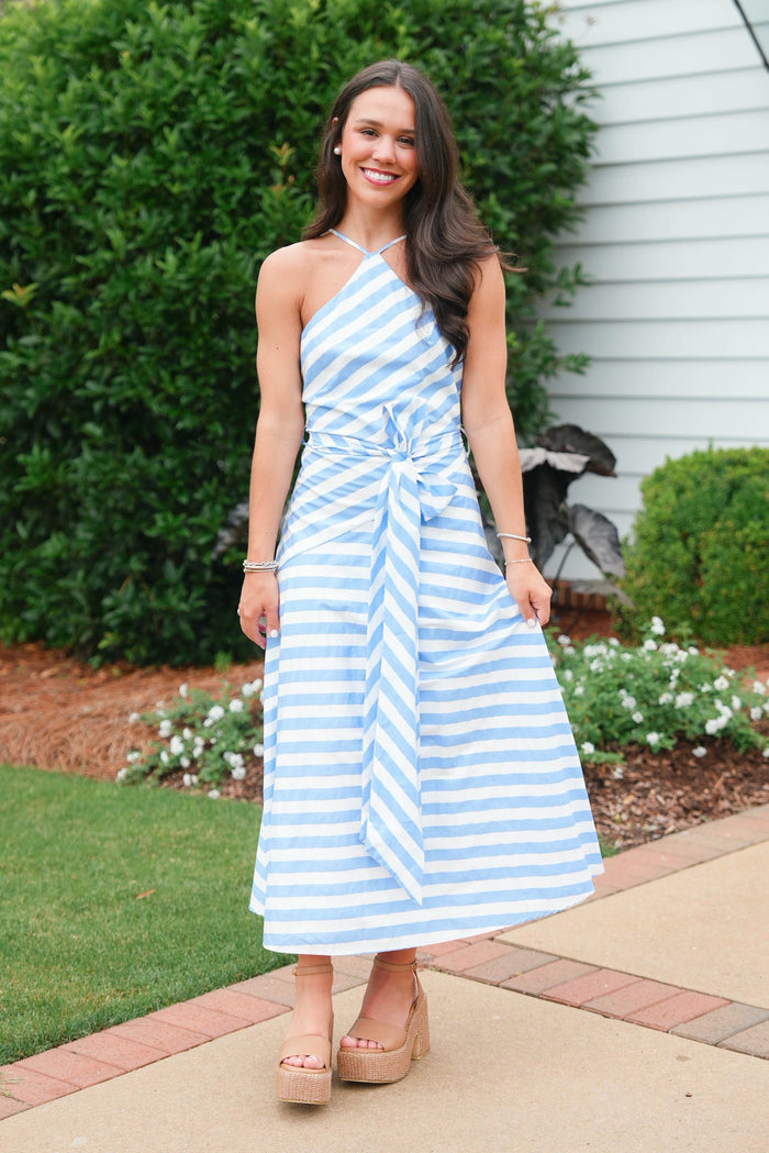 Woman wearing a blue and white striped dress standing outdoors.