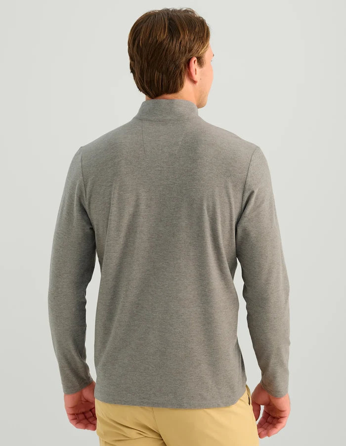 A man viewed from the back wearing a heather gray long-sleeve quarter-zip pullover and tan pants, set against a solid light gray background.
