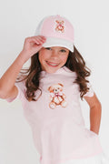 Young girl wearing a pink outfit with teddy bear designs on a white background