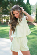 Woman in light green outfit standing outdoors with trees in the background