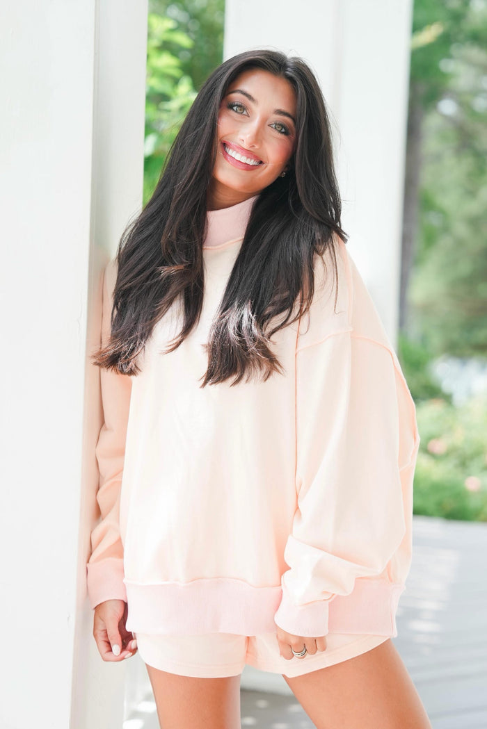 Woman wearing a light pink dress with long sleeves in an outdoor setting