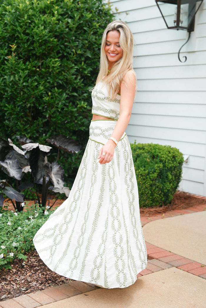 Woman in a white dress standing outdoors next to a house.