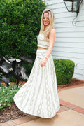 Woman in a white dress standing outdoors next to a house.