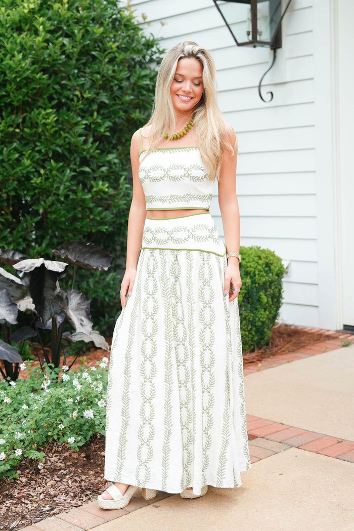 Woman in a white lace outfit standing outdoors next to a house.