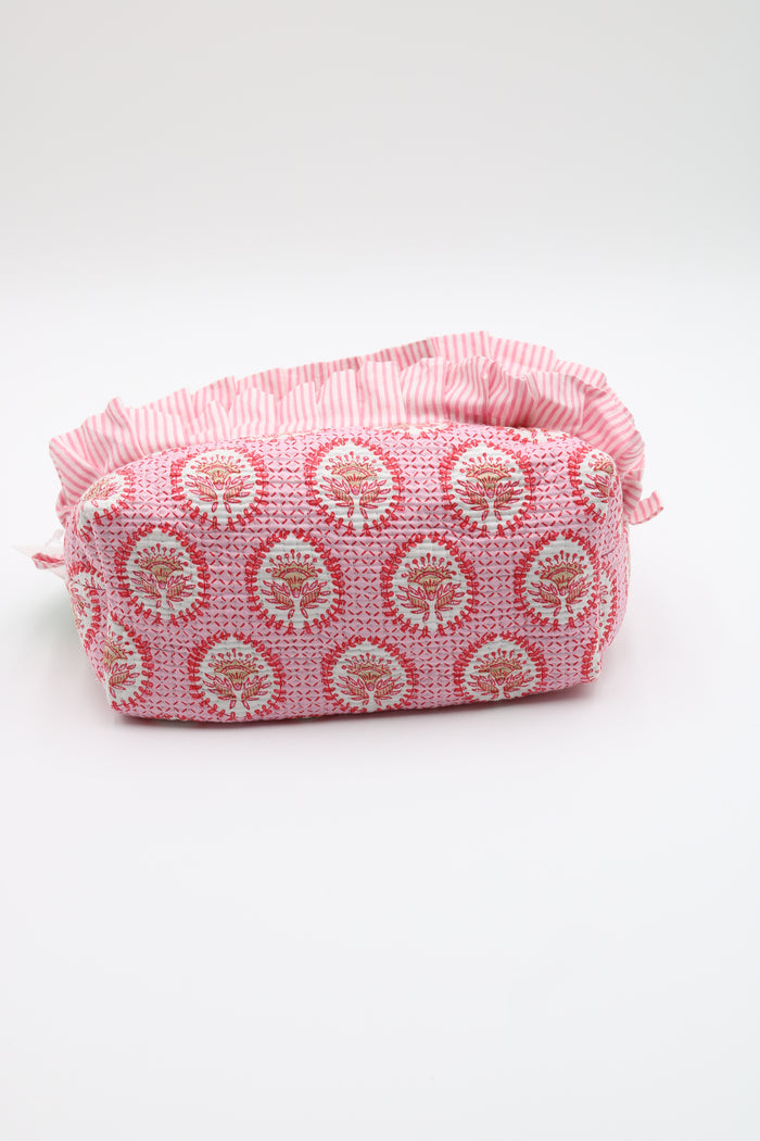 A pink and white patterned fabric pouch with a ruffled top edge, photographed on a clean white background.