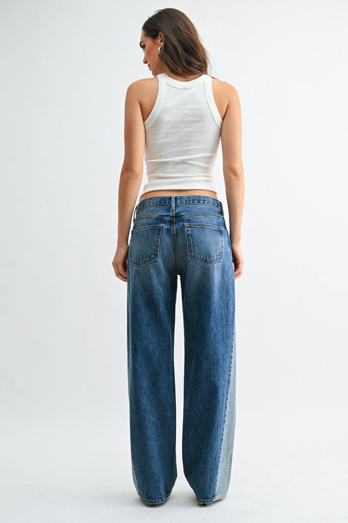 Woman wearing a white tank top and blue jeans on a white background