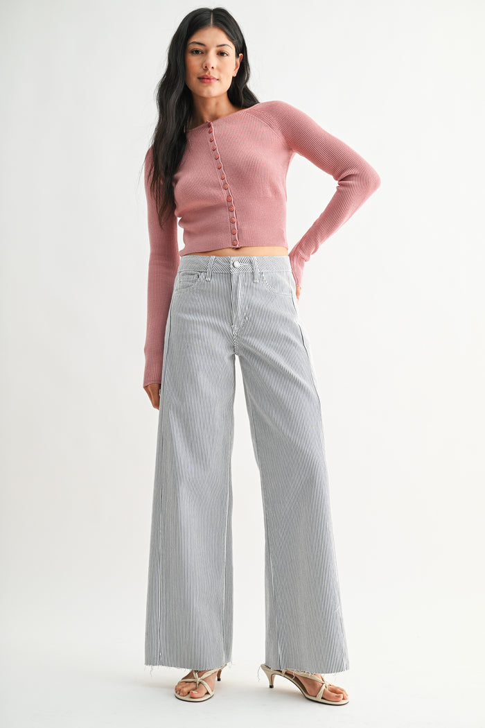 Woman wearing a pink cropped sweater and light blue jeans on a white background