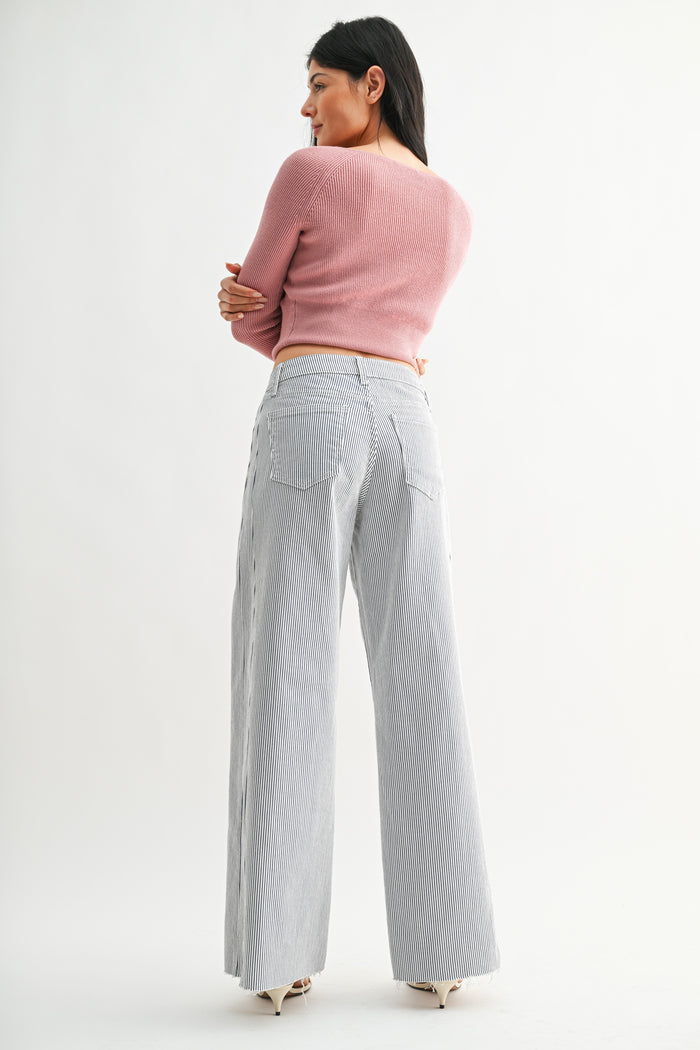 Woman wearing a pink sweater and gray checkered pants on a white background