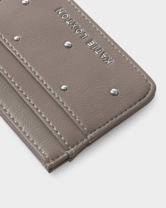 Close-up of a beige leather cardholder with studded details on a light gray background