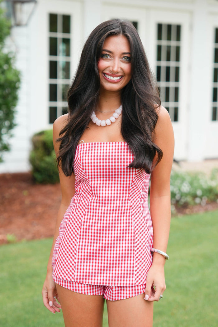Woman wearing a red and white checkered dress standing outdoors.