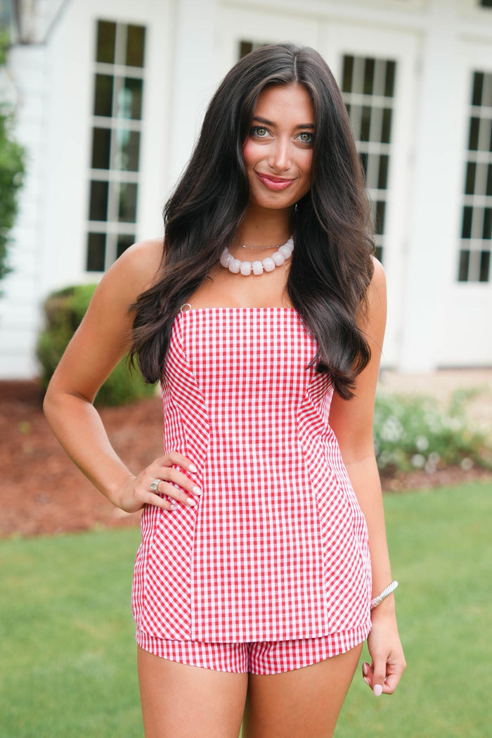 Woman wearing a red and white checkered dress outdoors.