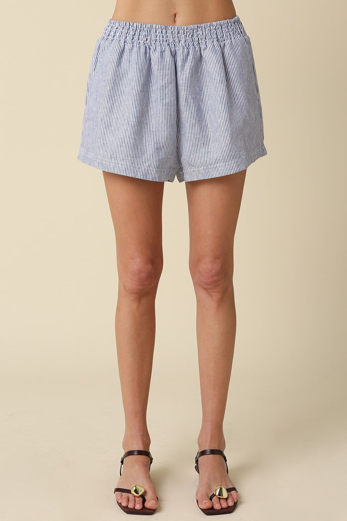 Blue and white checkered shorts worn by a person on a beige background