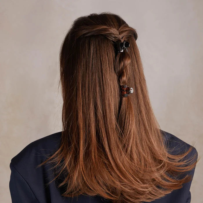 Long brown hair with a decorative hair clip against a neutral background