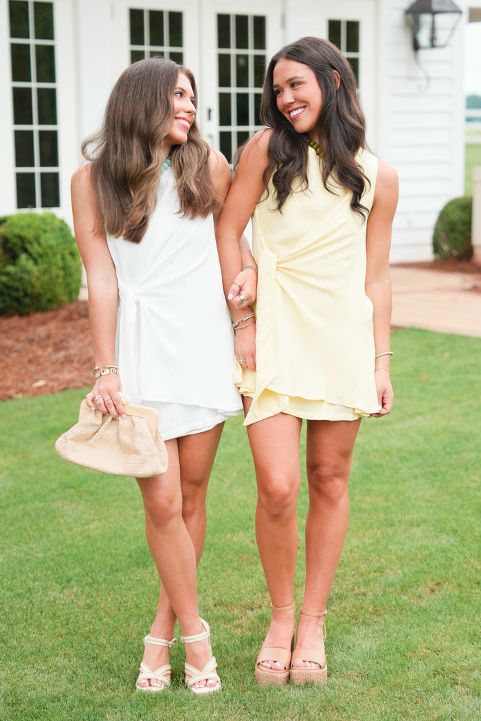 girl wearing a yellow dress standing next to a girl wearing white dress