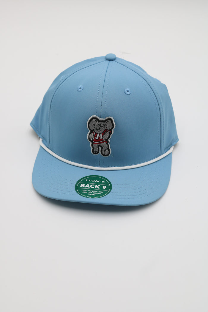 A light blue flat-brim cap with a white piping detail and a central embroidered patch of a cartoon bear holding a red heart. A green circular sticker is visible on the brim.