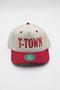 A structured baseball cap with an off-white crown and a red visor, featuring 'T-TOWN' embroidered in red across the front. A green circular HTA sticker is visible on the red visor.