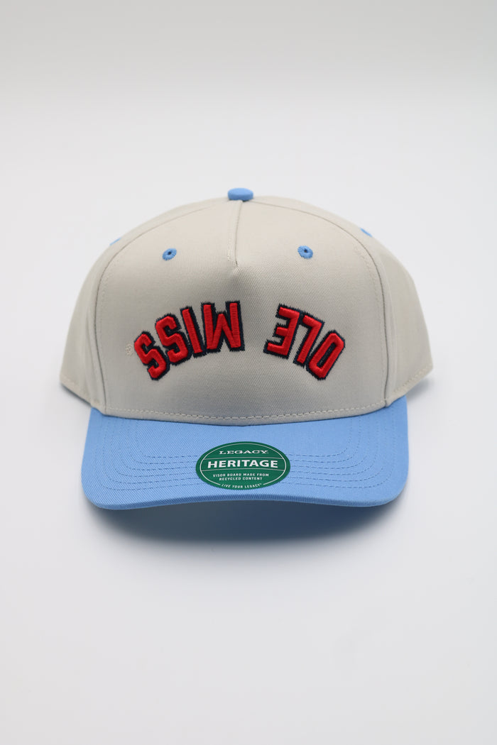 A baseball cap with a light gray crown, a light blue visor, and red embroidered text reading 'OLE MISS 370' outlined in black on the front. A green oval Heritage brand sticker is visible on the brim.
