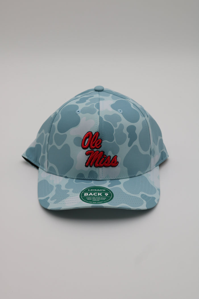A light blue and white camouflage baseball cap featuring 'Ole Miss' embroidered in red on the front, with a green oval sticker on the brim.