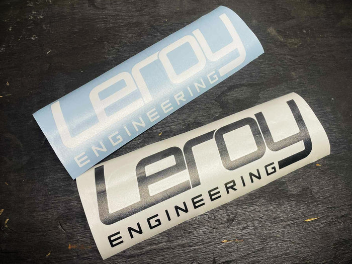 Two 'Leroy Engineering' stickers on a dark surface