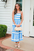 Woman in a blue and white striped dress standing outside a house.
