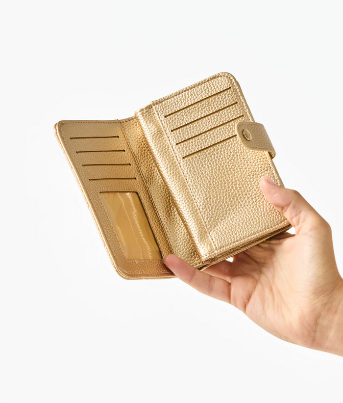 Gold wallet held in a hand against a white background