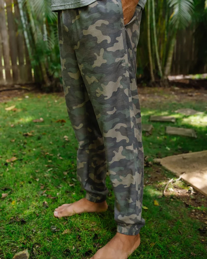 Person wearing camouflage pants standing on grass with a natural background