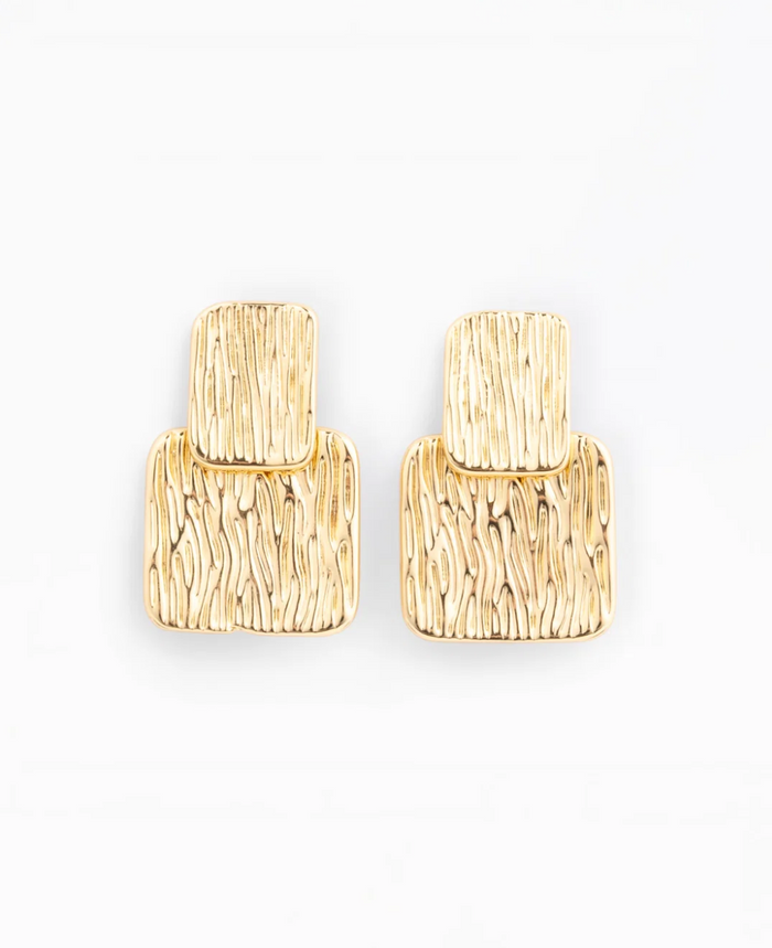 A pair of gold textured drop earrings with a layered, geometric design, photographed on a clean white background.