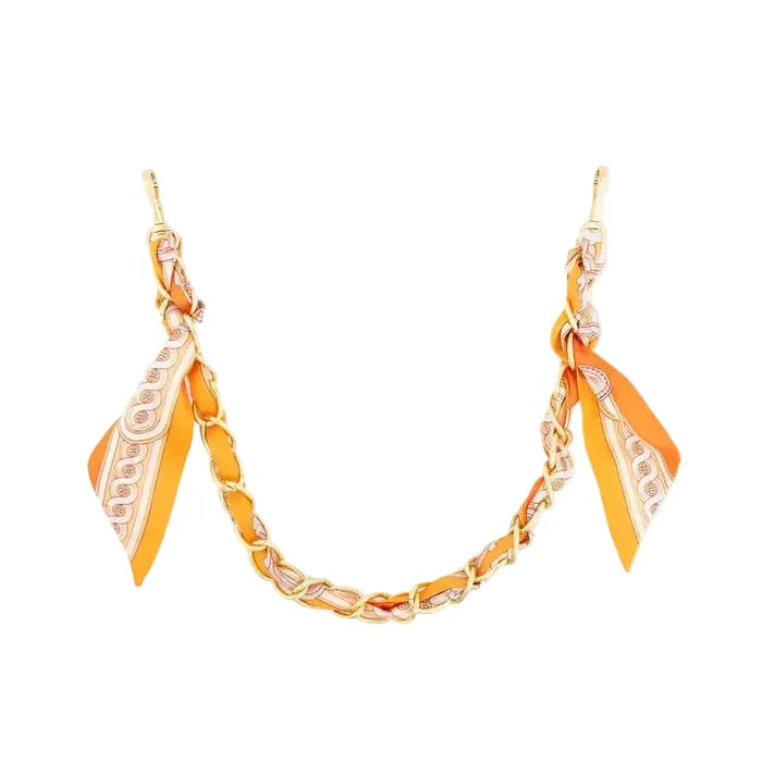 An orange and gold chain necklace with matching orange and white patterned silk scarf ends, displayed on a clean white background.