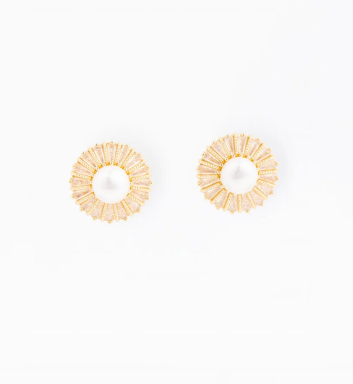 A pair of gold-toned circular earrings with a textured sunburst pattern surrounding a central white pearl, displayed on a clean white background.
