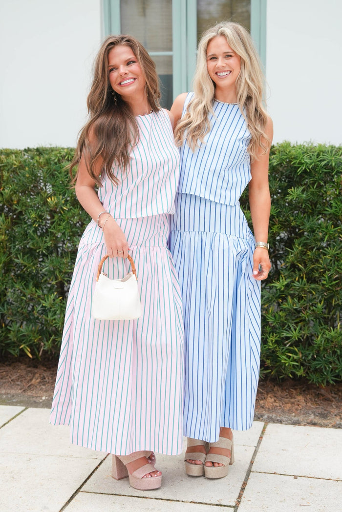 Two women in matching striped outfits standing outdoors.
