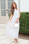 Woman in a white and green striped dress standing outdoors.