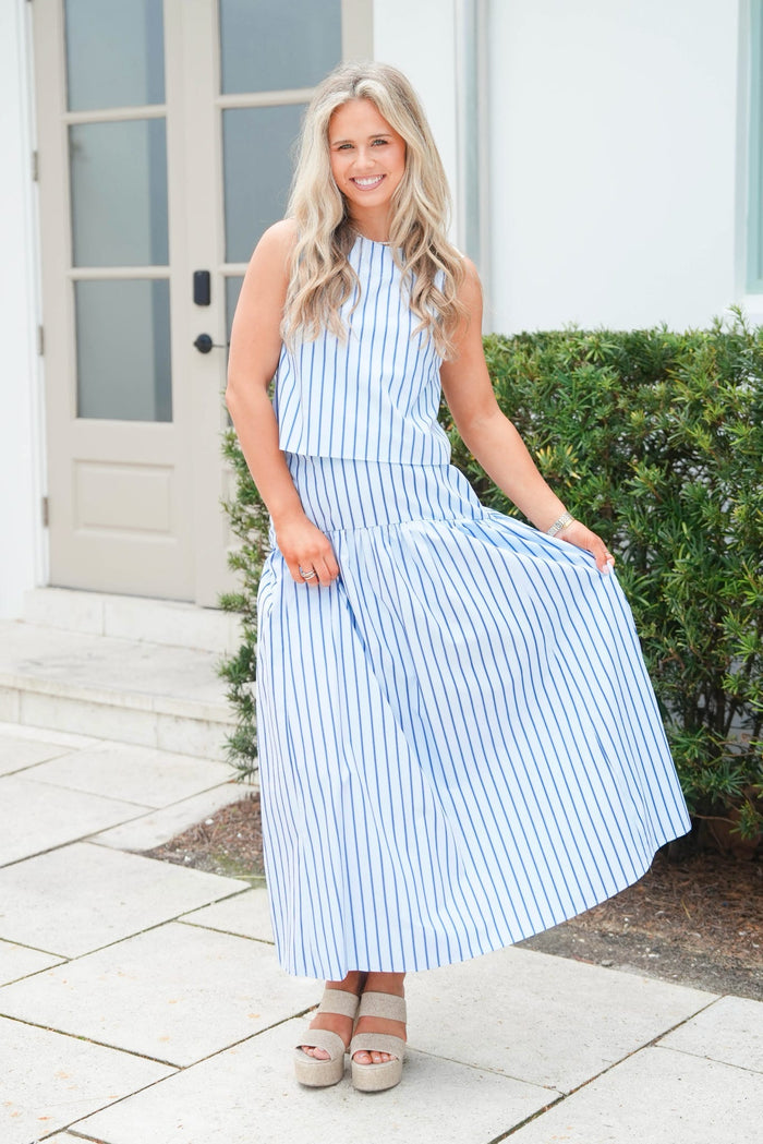 Woman wearing a blue and white striped dress standing outdoors.